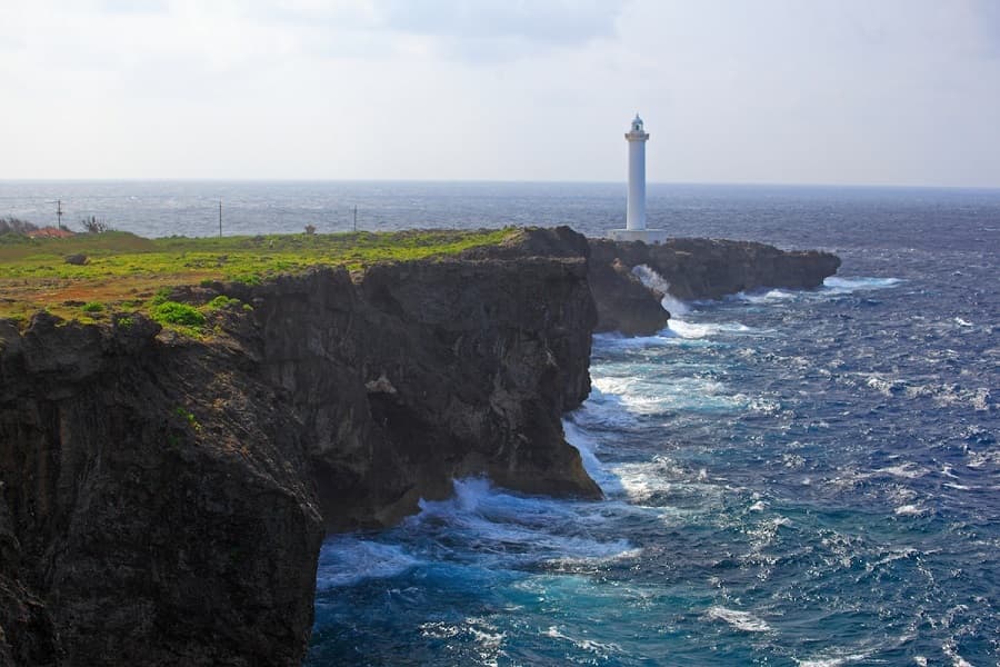 Cape Zanpa in okinawa, Japan - A dramatic coastal promontory on Okinawa's western shore featuring towering limestone cliffs, a historic white lighthouse, crystal-clear waters, and spectacular sunset views over the East China Sea
